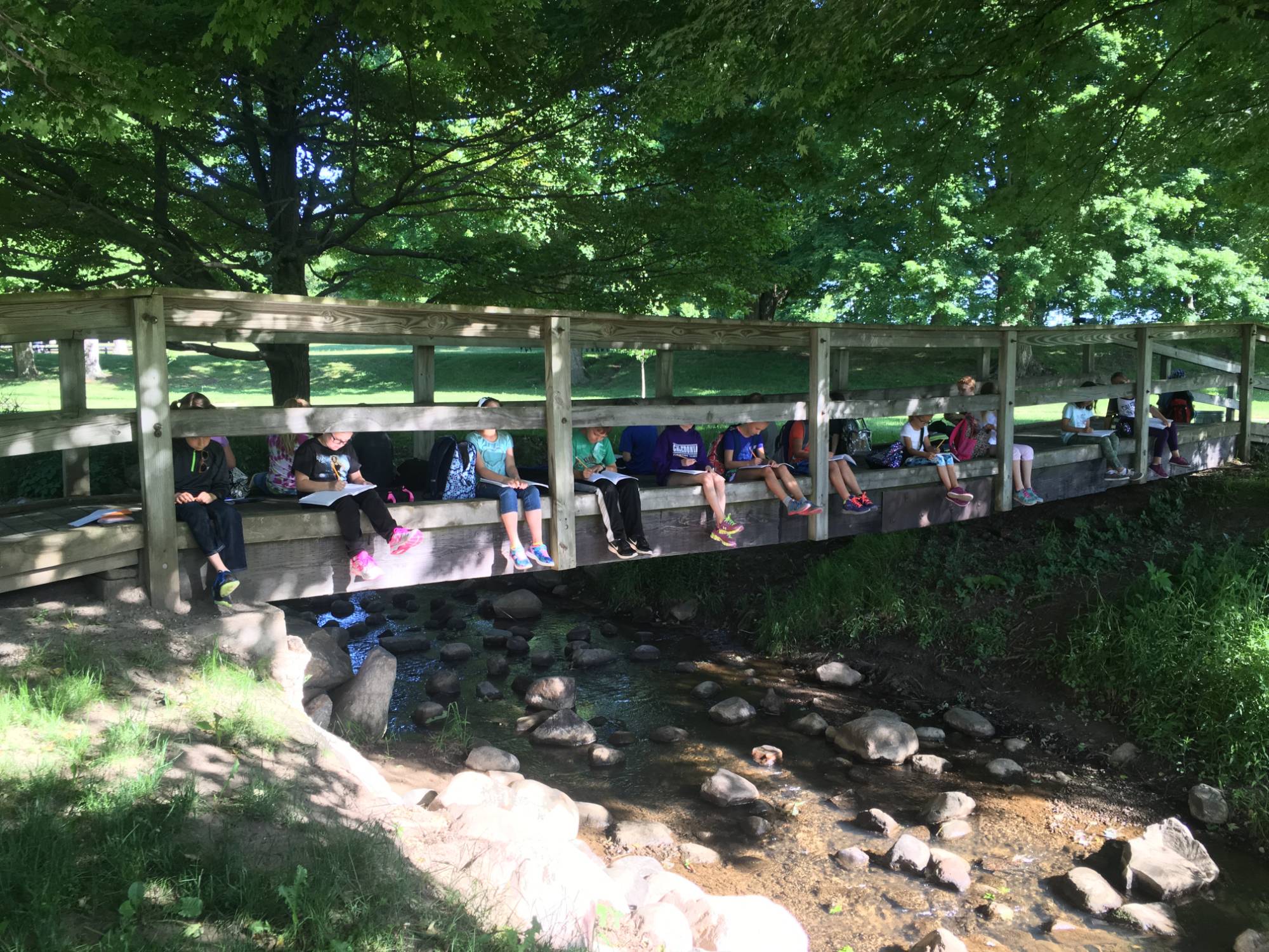 Students sit on bridge above stream